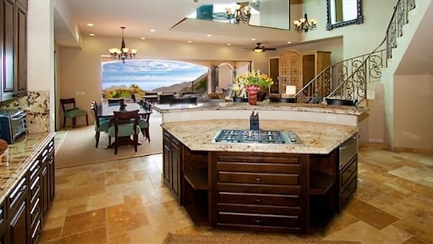 A spacious kitchen with a large island, a dining area, and a staircase leading to another level.