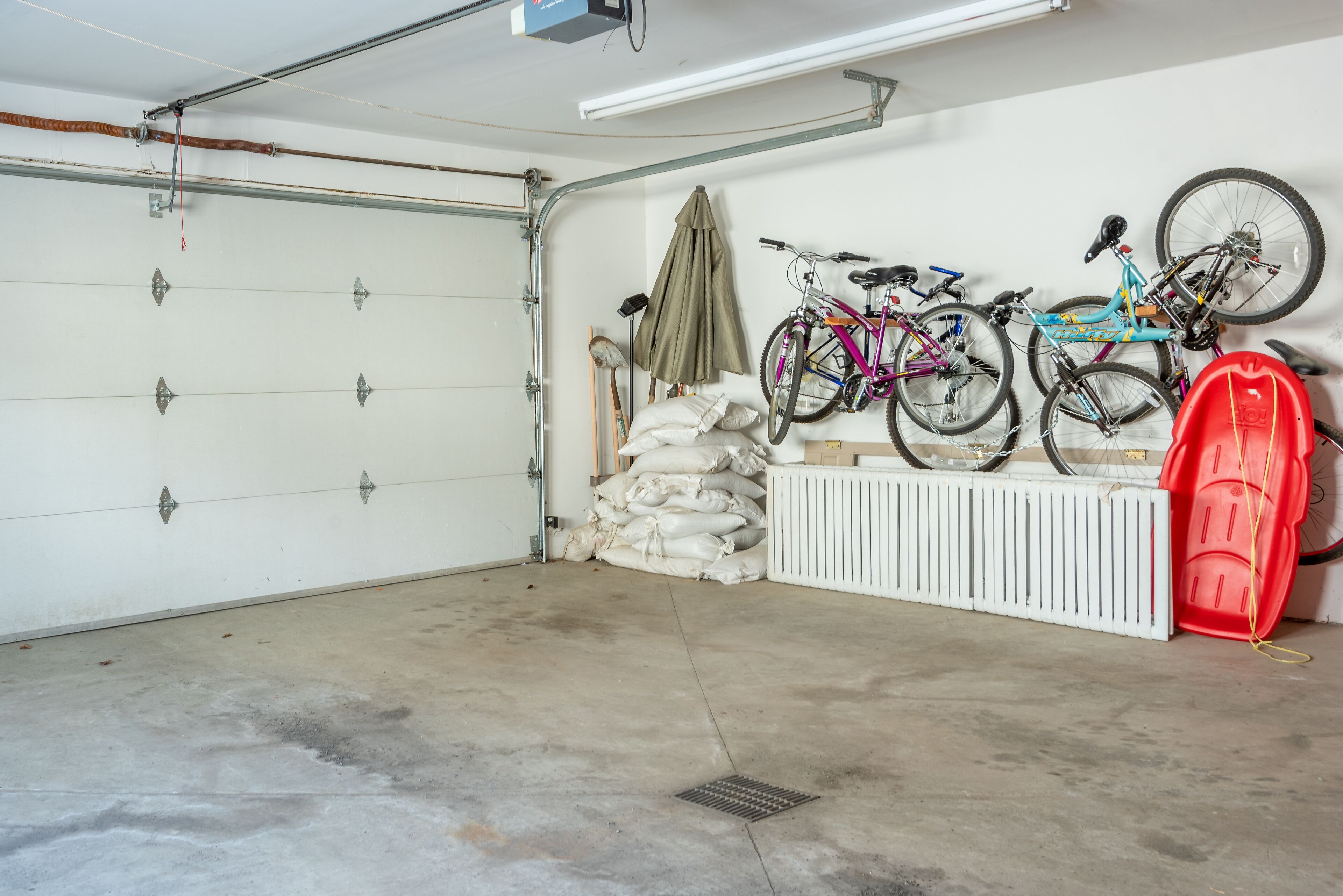 A garage with a white door, concrete floor, and several bicycles mounted on a wall.
