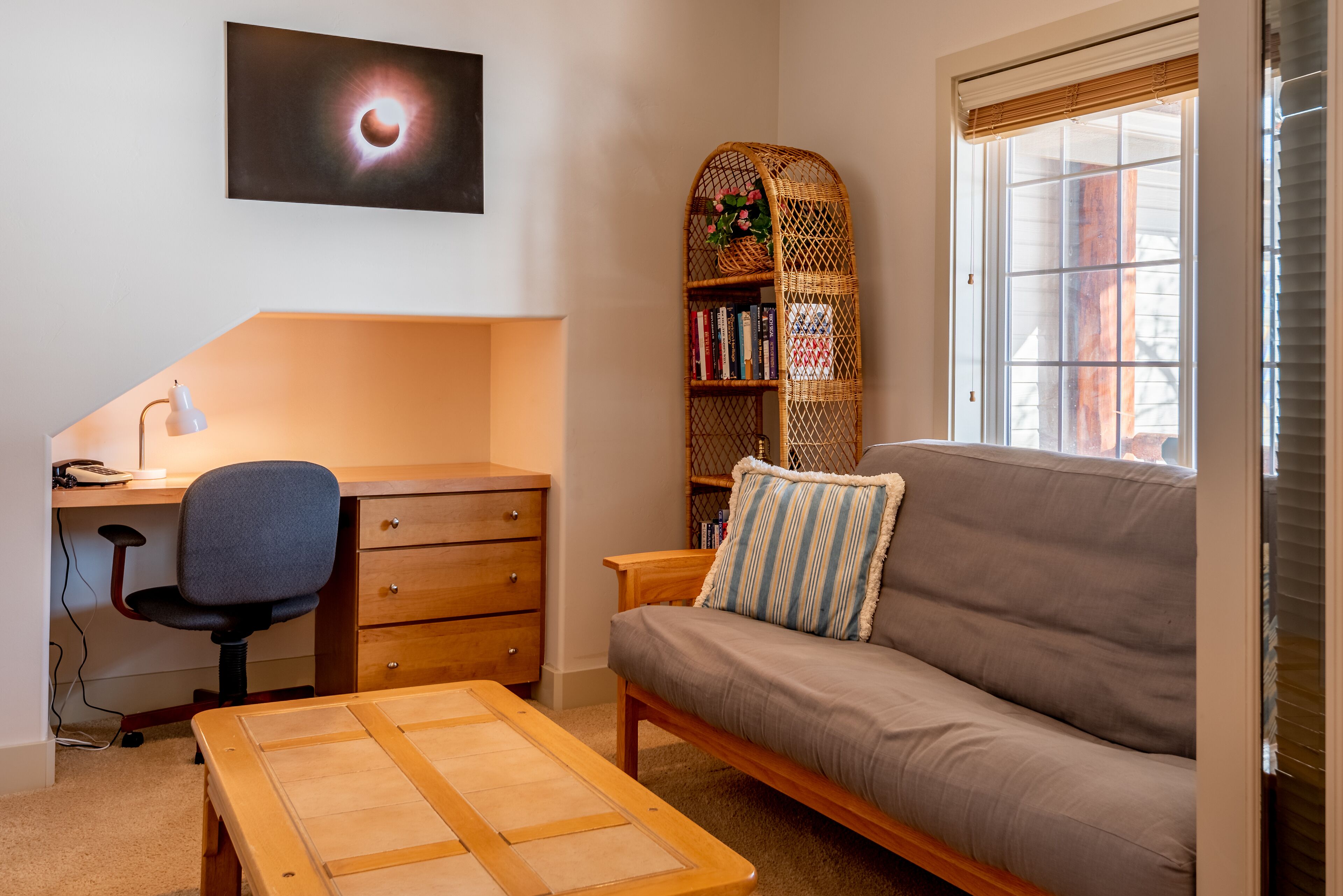 A room with a desk, chair, sofa, and a bookshelf.