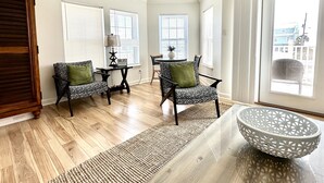 A spacious living room with hardwood floors, a large window, and a view of the city. - “Sea La Vie” Water Views,  Steps to the beach (Navarre Beach)