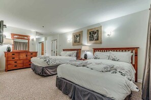 Hotellihuone, jossa on kaksi sänkyä, puinen lipasto, peili ja taideteoksia seinillä.