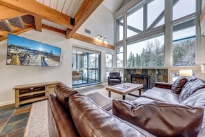 A spacious living room with a large window, a fireplace, and a leather sofa.