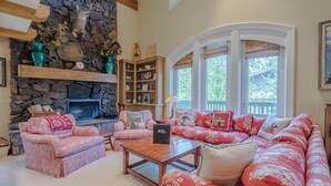 A cozy living room with a stone fireplace, a large red sofa, and a wooden coffee table. - Lodge Apt. II 886 - Perfect for Families Sun Valley Resort Style & Amenities (Sun Valley)