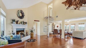 Un salon spacieux avec une cheminée, un escalier et un coin repas.