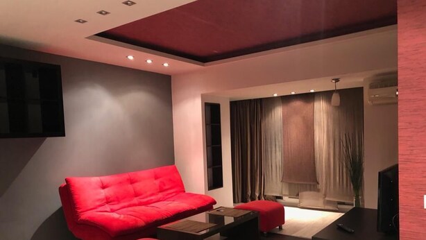 Ein modernes Wohnzimmer mit einem roten Sofa, einem Couchtisch und einem Fernseher.