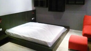 Ein modernes Schlafzimmer mit einem Bett, einem roten Sessel und einer Wand mit Einbauschränken.