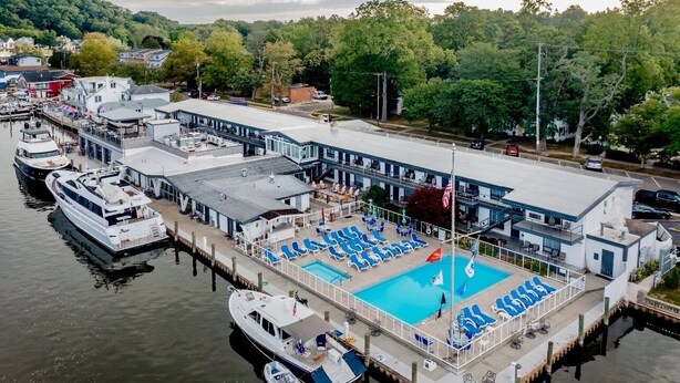 Un hotel sul lungomare con piscina, imbarcazioni ormeggiate e vista sulla zona circostante.