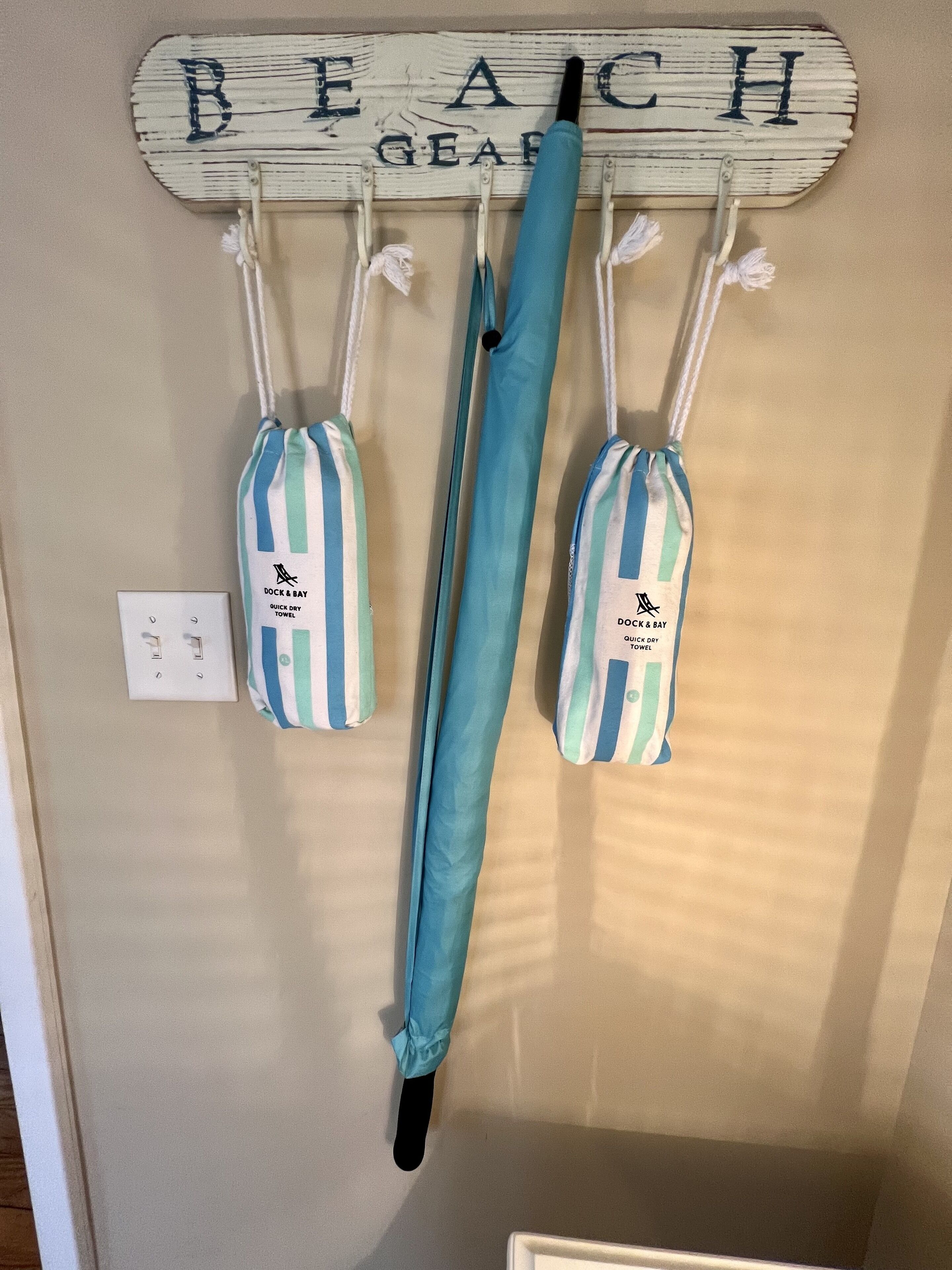 A wall-mounted rack with two striped beach towels and a pair of jeans hanging.