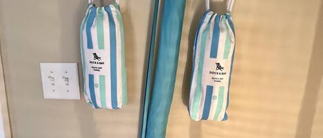 A wall-mounted rack with two striped beach towels and a pair of jeans hanging.