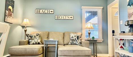 A living room with a sofa set, two lamps, a small side table, and wall decorations.