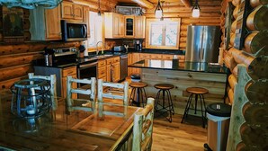Una cocina estilo cabaña con armarios de madera, un refrigerador de acero inoxidable y una zona de bar con taburetes.