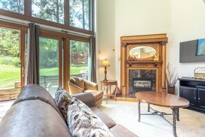 A spacious living room with a fireplace, large windows, and a cozy seating area. - Ski-in/Walk-out condo,  free wifi, covered parking. kitchen, pet friendly! (Copper Mountain)