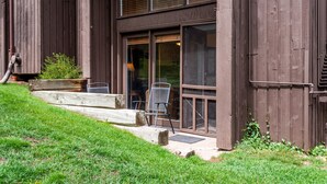 Un edificio de madera con ventanas amplias y un pequeño espacio al aire libre con sillas.