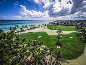 A golf course with a beach, palm trees, and a clear view of the ocean. - Los Ensueños: Dream villa near beach w/ pool, Jacuzzi, housekeeper & golf cart (Punta Cana)