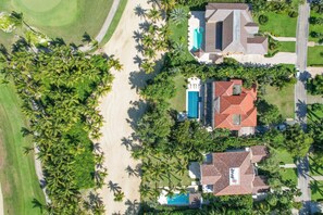 Vue aérienne d’un quartier résidentiel avec des maisons, une piscine et des palmiers.