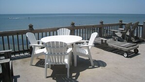 Une terrasse avec une table et des chaises, donnant sur une étendue d’eau.