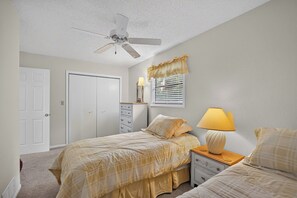 Un dormitorio con cama, mesitas de noche, ventilador de techo, armario y ventana con persianas.