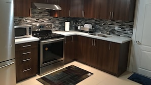 Una cocina moderna con armarios de madera oscura, electrodomésticos de acero inoxidable y salpicadero de azulejos.