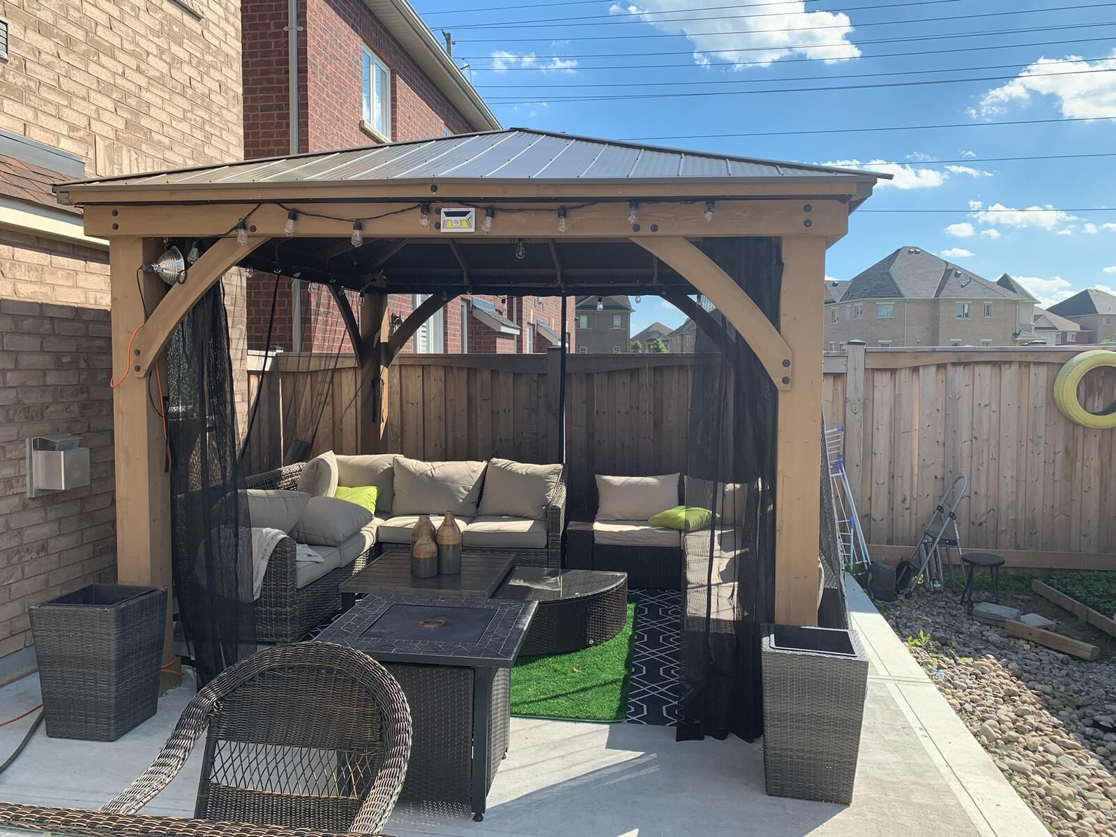 Un'area patio coperta con un'accogliente zona salotto imbottita, un tavolo e una pergola.