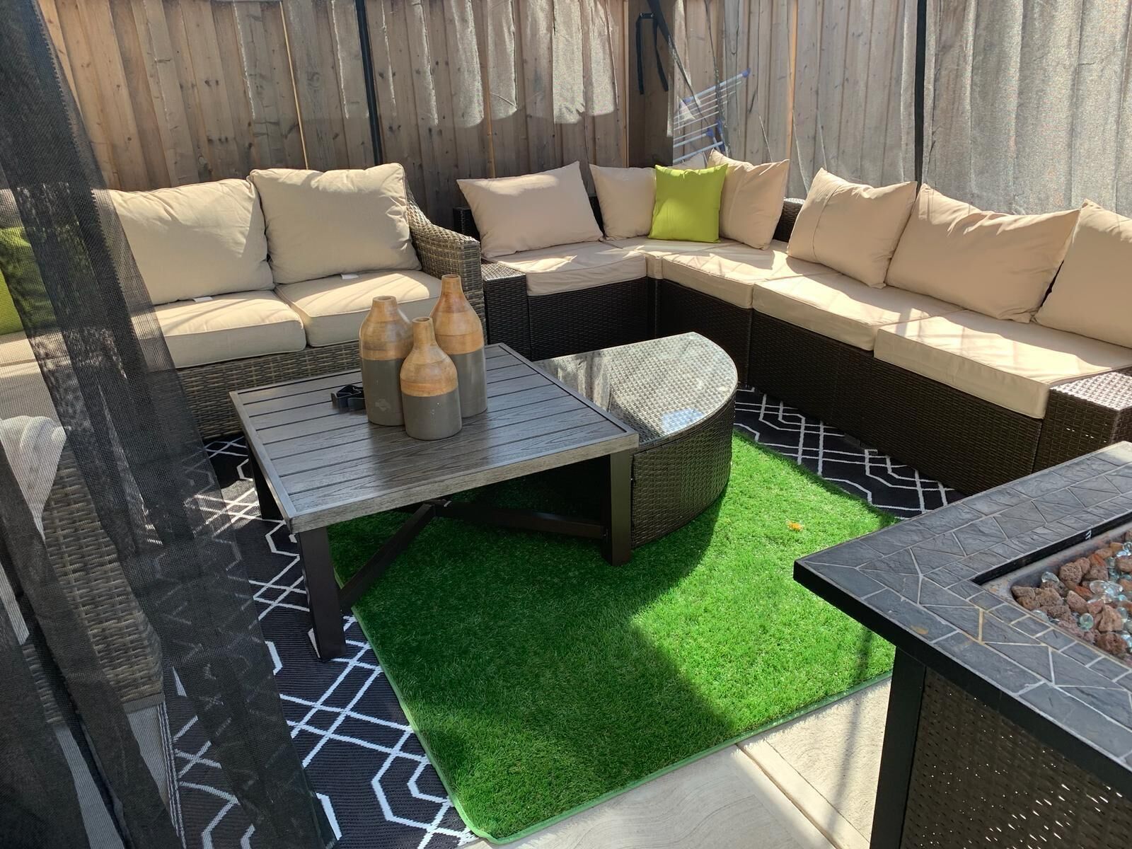 An outdoor seating area with a sectional sofa, a round table, and a fire pit.