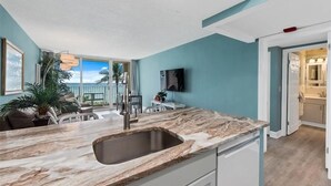 Een moderne keuken met een groot eiland, een ingebouwd spoelgedeelte en uitzicht op het buiten.