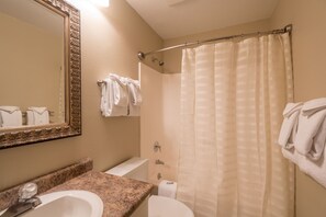 A bathroom with a sink, toilet, and shower curtain.
