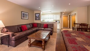 Un salon avec un canapé d’angle, une table basse en bois et un tapis rouge à motifs.