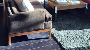 Een gezellige woonkamer met een open haard, een bank, een bijzettafeltje met boeken en een decoratieve spiegel.