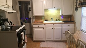 Una cocina compacta con gabinetes blancos, encimera de madera, un fregadero y una estufa.