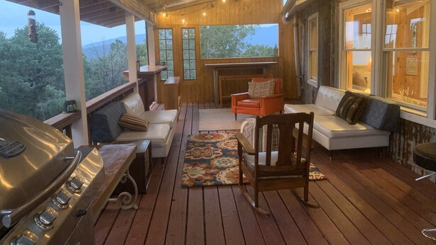 A covered outdoor area with a grill, seating, and a fireplace.