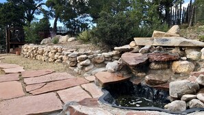 A stone water feature with a small pond, surrounded by rocks and a stone wall.