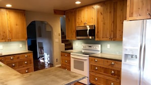 A kitchen with wooden cabinets, a stainless steel refrigerator, a microwave, and a stove.