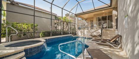 A swimming pool with a glass enclosure, steps leading into the pool, and lounge chairs.