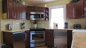 Una cocina moderna con electrodomésticos de acero inoxidable, armarios de madera y un ventanal que aporta luz natural.