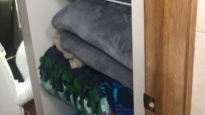 Un espace de rangement avec des étagères où sont pliés des serviettes et un panier contenant des vêtements pliés.