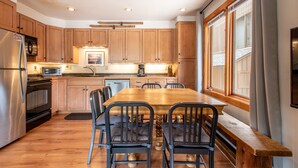 A modern kitchen with wooden cabinets, a stainless steel refrigerator, a built-in oven, a microwave, and a dining table with chairs. - Nice Ski-in/Walk-out condo, free wifi, & parking. (Copper Mountain)