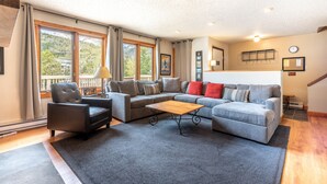A spacious living room with a grey sofa set, a wooden coffee table, and a black armchair. - Nice Ski-in/Walk-out condo, free wifi, & parking. (Copper Mountain)