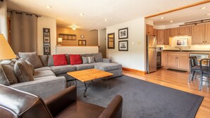 A modern living room with a grey sectional sofa, a wooden coffee table, and a grey carpet. - Nice Ski-in/Walk-out condo, free wifi, & parking. (Copper Mountain)