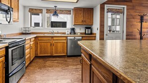 Una cocina con armarios de madera, un refrigerador de acero inoxidable, lavavajillas y encimera de granito.