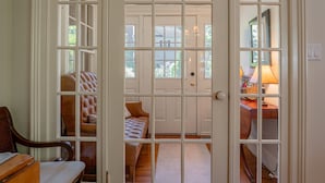 A room with a large window, a wooden desk, a chair, and a bed with a leather headboard. - Arbour House, 1830 Historic Home (Niagara-on-the-Lake)