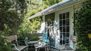 A wooden deck with a table and two benches, surrounded by lush greenery. - Arbour House, 1830 Historic Home (Niagara-on-the-Lake)
