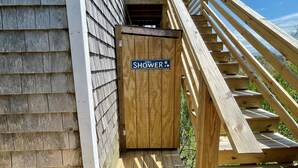 A wooden staircase leading to a wooden door with a sign that reads "Shower". - Kith And Kin:  Old Ocracoke style cottage, spacious screened porch. (Ocracoke)