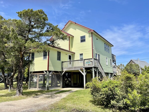 A two-story yellow building with a red roof, a balcony, and a wooden porch.