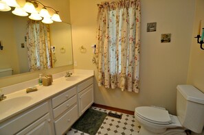 A bathroom with a white sink, a mirror, a toilet, and a shower curtain.