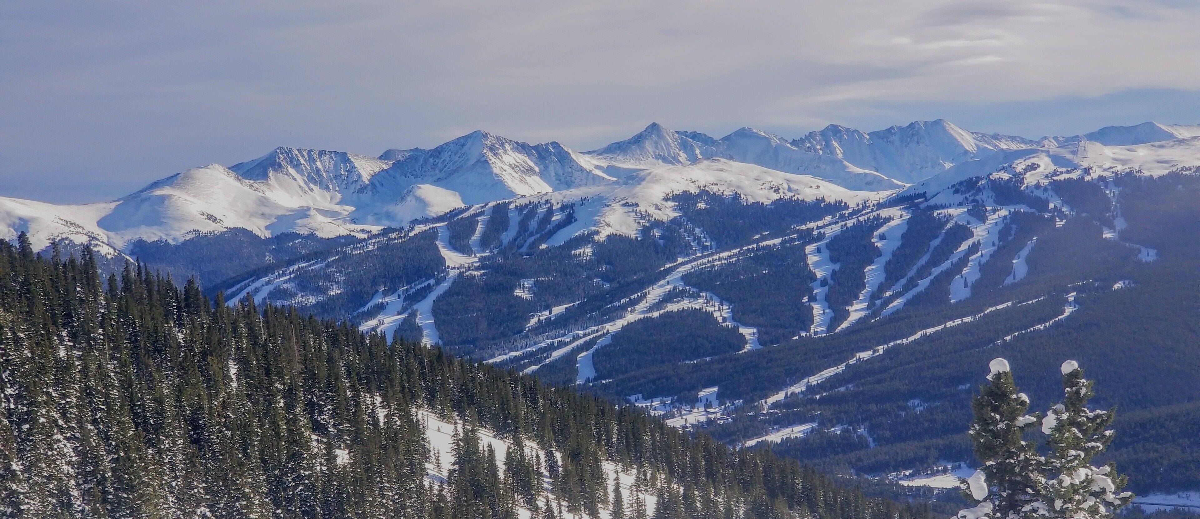 A mountainous landscape with snow-covered peaks and dense forests.