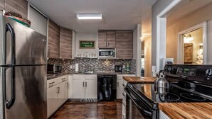 Eine moderne Küche mit Edelstahlgeräten, einer Holz Arbeitsplatte und einer gefliesten Spritzschutzwand.