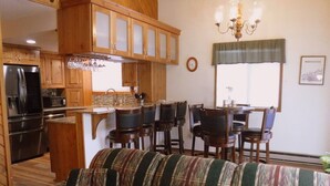 Ein gemütliches Wohnzimmer mit einer gestreiften Couch, Holzschränken und einem Essbereich mit Stühlen und einem Tisch.