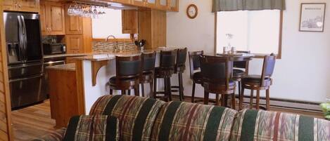 A cozy living room with a striped sofa, wooden cabinets, and a dining area with chairs and a table.