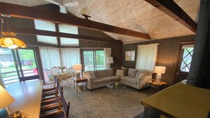 Una sala de estar acogedora con techo de madera, un comedor con mesa y sillas, y un conjunto de sofá.