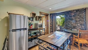 Une cuisine avec un réfrigérateur en acier inoxydable, une table en bois et un mur en pierre.